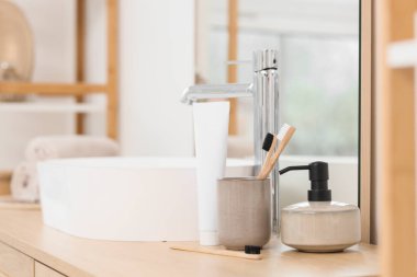 Banyoda lavabonun yanında duran bambu diş fırçası ve yapıştırıcılı tutucu.