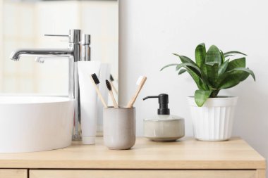 Banyoda lavabonun yanında duran bambu diş fırçası ve yapıştırıcılı tutucu.