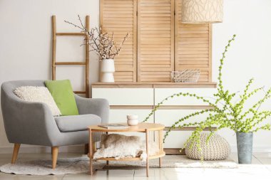 Gri koltuğu, sehpası ve çiçek açan ağaç dalları olan şık bir oturma odası.