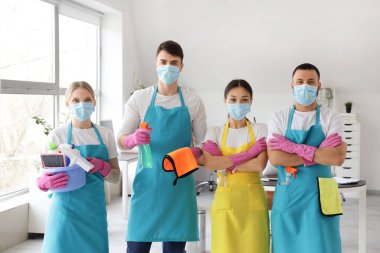 Ofiste temizlik malzemesi taşıyan maskeli hademe takımı.