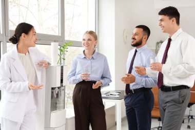 Ofiste soğutucu yakınında su bardakları olan bir grup iş adamı.