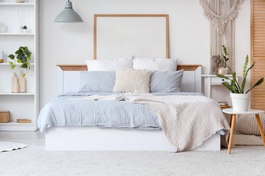 Konforlu yataklı, komodinli, çiçekli ve raflı bir yatak odası.