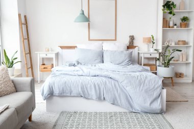 Konforlu yatağı, raf ünitesi ve çiçekleri olan hafif yatak odasının içi.