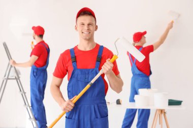 Odada boya silindiri olan erkek dekoratör.