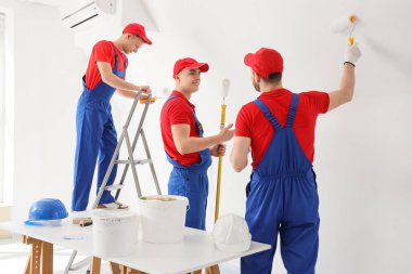 Erkek dekoratörlerden oluşan bir ekip odayı boyuyor.