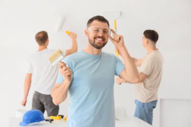 Güvenlik gözlüklü ve odada boya fırçası olan genç adam.