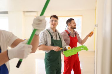 Erkek dekoratörlerden oluşan bir ekip odayı boyuyor.