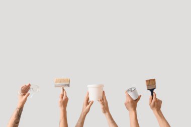 Açık arkaplanda ressam aletleri olan erkek eller