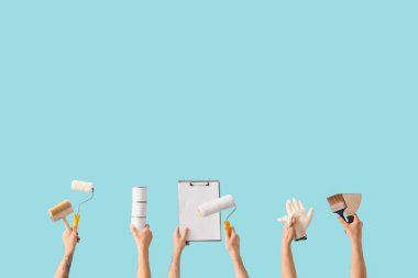 Mavi arka planda boyacı aletleri ve panosu olan erkek eller