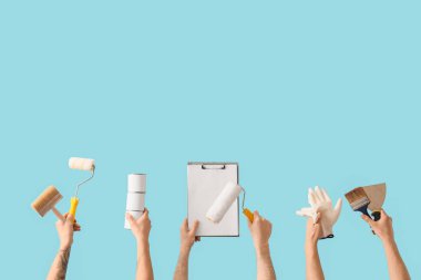 Mavi arka planda boyacı aletleri ve panosu olan erkek eller