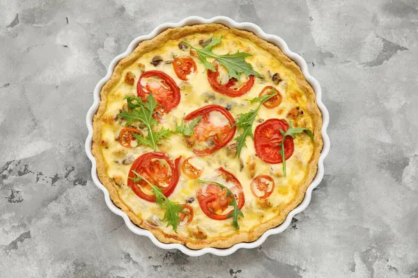 Gri arka planda roka yapraklı lezzetli domates tartı.