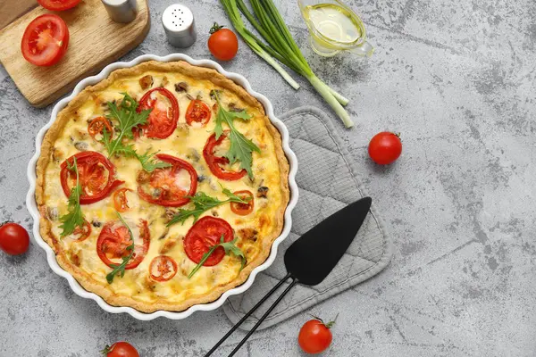 Lezzetli roka yapraklı domates tartı ve gri arkaplanda yeşil soğan.