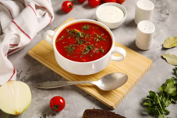 Bir kase lezzetli Ukrayna çorbası ve gri arka planda malzemeler, yakın plan.