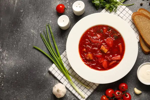 Bir kase lezzetli Ukrayna çorbası ve koyu arkaplanda malzemeler.