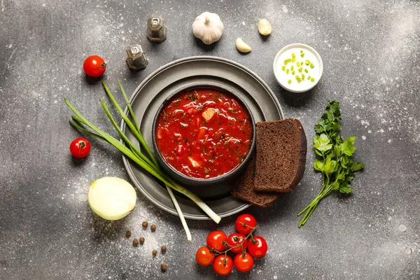 Ekmek dilimleri ve koyu arkaplanda malzemelerle bir kase lezzetli Ukrayna çorbası.