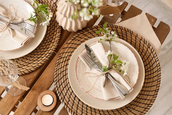 Tabakları, yanan mumları ve çiçek açan ağaç dalları olan zarif bir masa. Yakın plan.