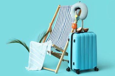 Bir bardak kokteyl, hindistan cevizi, iskemle, havlu ve renkli yastıklı çanta.