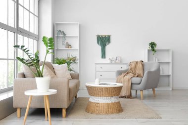 Oturma odasının içinde yumuşak kanepe, koltuk ve rattan masa var.