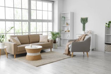 Oturma odasının içinde yumuşak kanepe, koltuk ve rattan masa var.