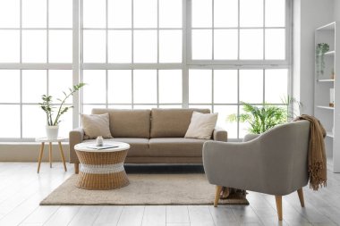 Oturma odasının içinde yumuşak kanepe, koltuk ve rattan masa var.