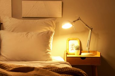 Geceleri yatak odasındaki kaktüs ve çerçeveli parlayan lamba.