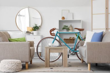 Oturma odasının içinde bisiklet, kanepe ve sehpa var.