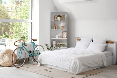 Bisiklet, klozet ve raf üniteli hafif yatak odasının içi