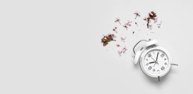 Alarm saati ve ışık arka planında çiçekler ve metin için yer var. Bahar geldi.