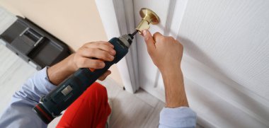Elektrikli matkapla çalışan erkek işçi. Evinin kapısını onarıyor. Kapalı.