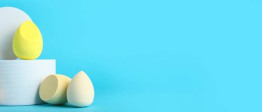 Mavi arka planda makyaj süngeri olan dekoratif podyumlar