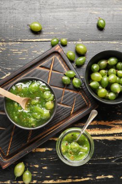 Lezzetli bektaşi üzümü reçelli kase ve kavanoz ve siyah ahşap arka planda taze böğürtlen.