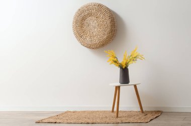 Beyaz duvarın yanındaki sehpanın üzerinde güzel mimoza çiçekleri olan vazo.