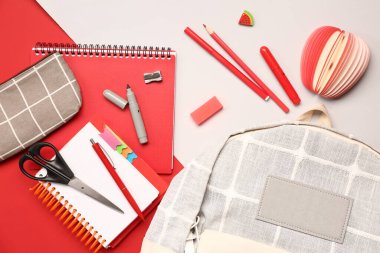 Renkli arka planda farklı kırtasiye malzemesi içeren şık bir okul çantası.