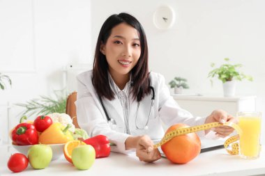 Ofisinde greyfurtlu ve mezuralı Asyalı kadın beslenme uzmanı