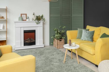 Oturma odasının içinde elektrikli şömine ve kanepe var.