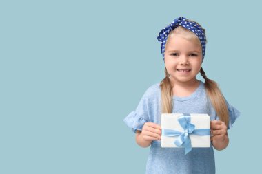 Mavi arka planda hediye kutusu olan şirin, mutlu küçük bir kız. Hanuka kutlaması