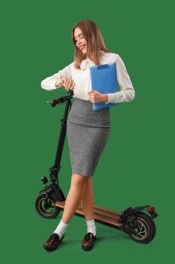 Yeşil arka planda panosu ve scooter 'ı olan şaşırmış bir iş kadını portresi