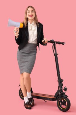 Portrait of young businesswoman with megaphone and kick scooter on pink background