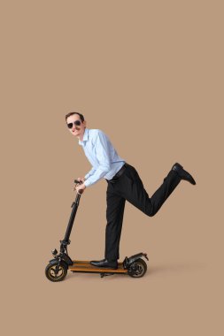 Bej arka planda scooter süren genç iş adamının portresi