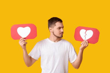 Sarı arka planda ikonları seven ve sevmeyen yakışıklı genç adam.