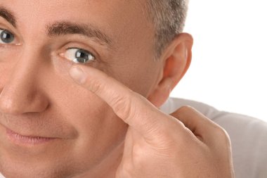 Olgun adam beyaz arka plana kontak lens takıyor, yakın plan.