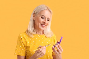 Makyaj pudrası ve arkaplan fırçası olan güzel olgun bir kadın.