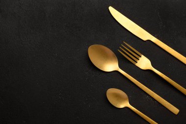 Siyah arka planda altın çatal bıçak takımı. Yakın çekim.