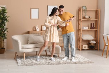 Güzel, genç bir çift oturma odasında dans ediyor.