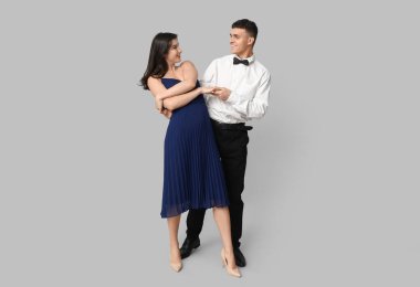 Gri arka planda dans eden güzel genç çift