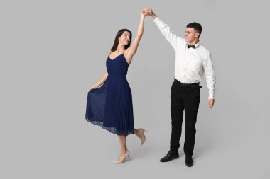 Gri arka planda dans eden güzel genç çift