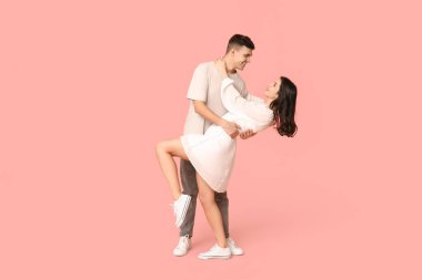 Pembe arka planda dans eden güzel genç çift