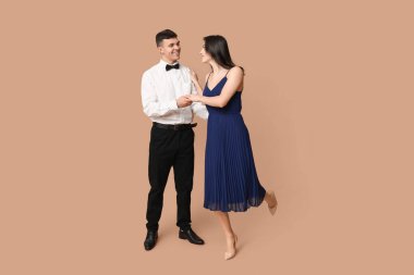 Kahverengi arka planda dans eden güzel genç çift