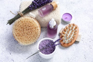 Hafif arka planda lavanta yağı şişeleri ve masaj vücut fırçalarıyla güzel bir kompozisyon, yakın plan.