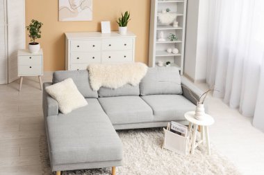 Gri kanepesi, sehpası, raf ünitesi ve resmi olan şık bir oturma odası.